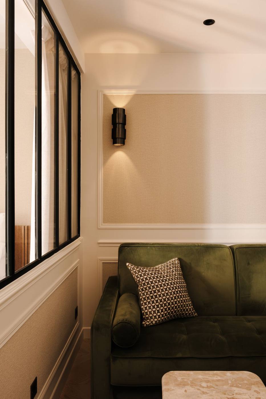 Canapé velours vert ouvert sur la chambre par la verrière